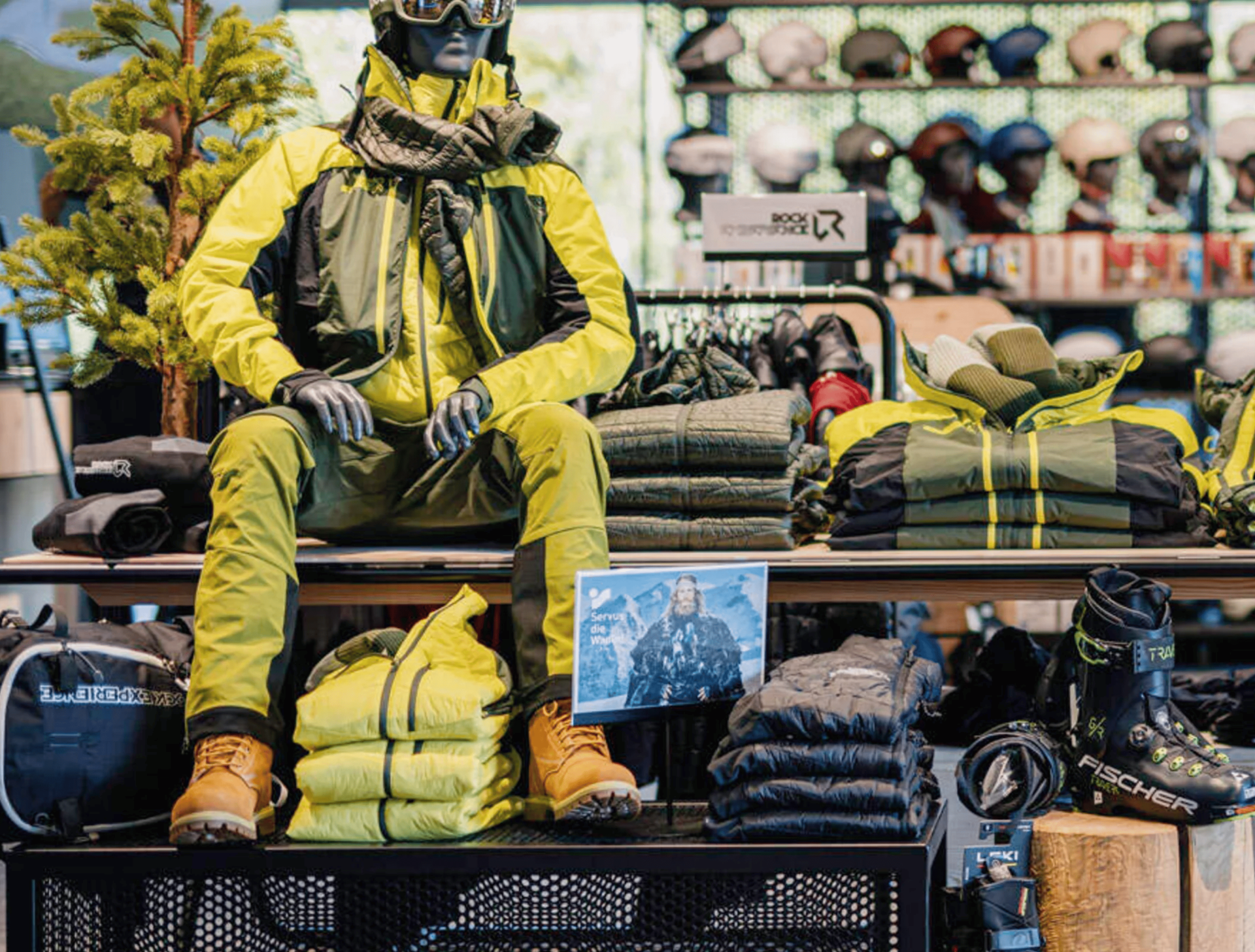 Sports shop with mannequin wearing yellow ski clothing, winter gear, helmets, and ski accessories.