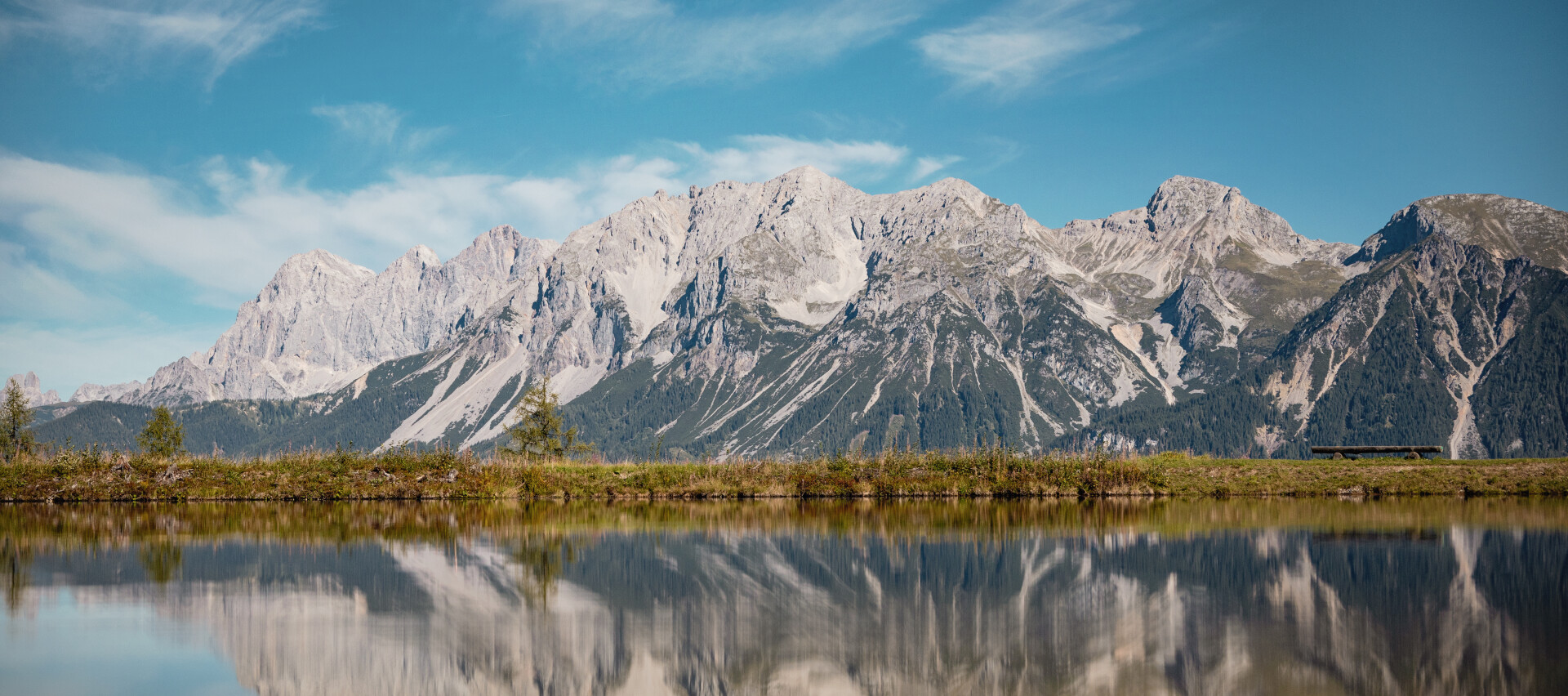 Dachstein-Gebirge mit Gipfeln, die sich perfekt in einem stillen See unter einem klaren blauen Himmel spiegeln. Da