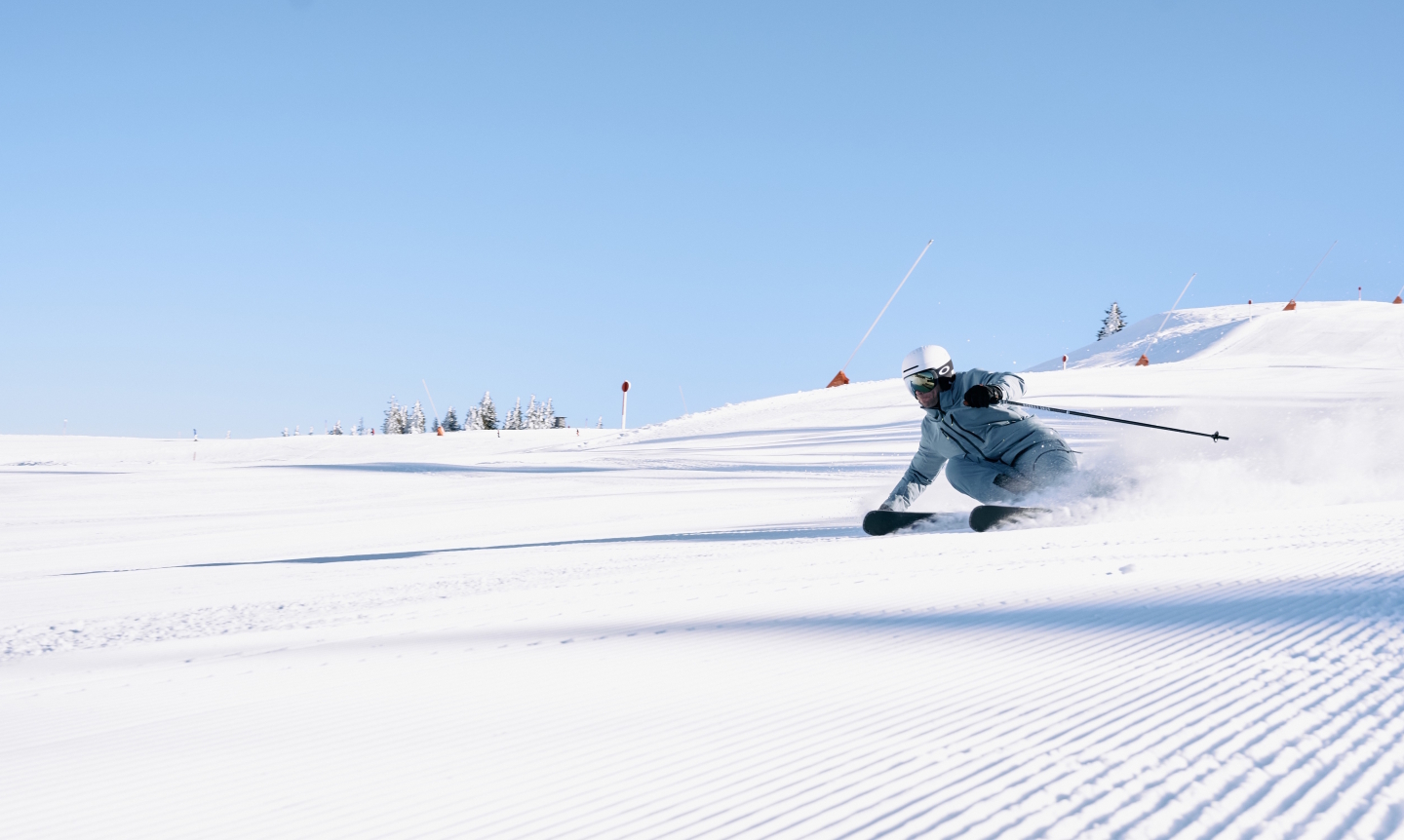 Skifahrer carvt an einem sonnigen Tag eine präparierte Skipiste hinunter. Wintersport und Erholung.
